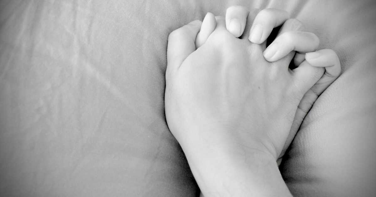 A photo of a woman's hand on a bed with an emphasis on sensual touch.