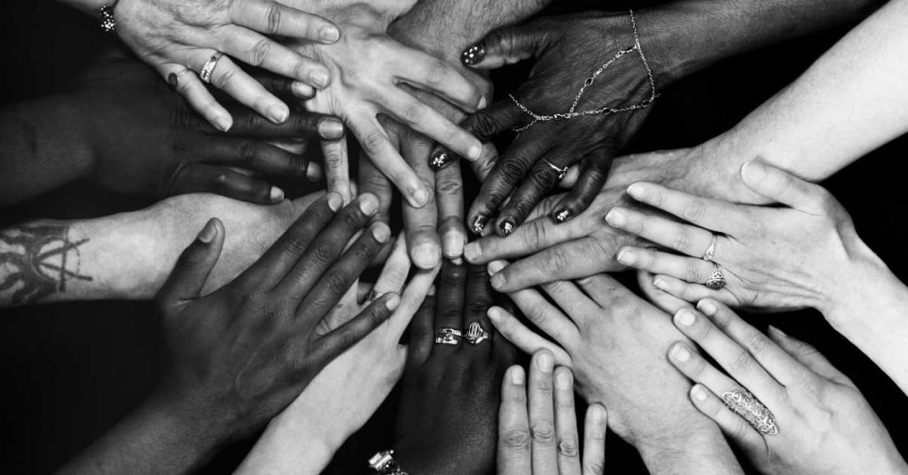 A black and white photo depicting a circle of hands, symbolizing healing.