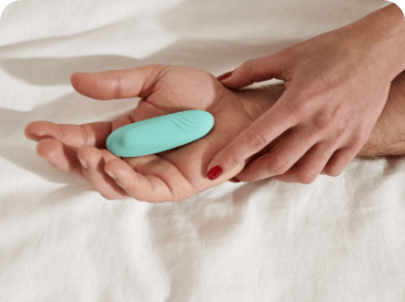 Two hands touching with small teal vibrator.