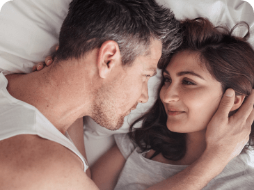 Couple in bed staring into each others eyes.